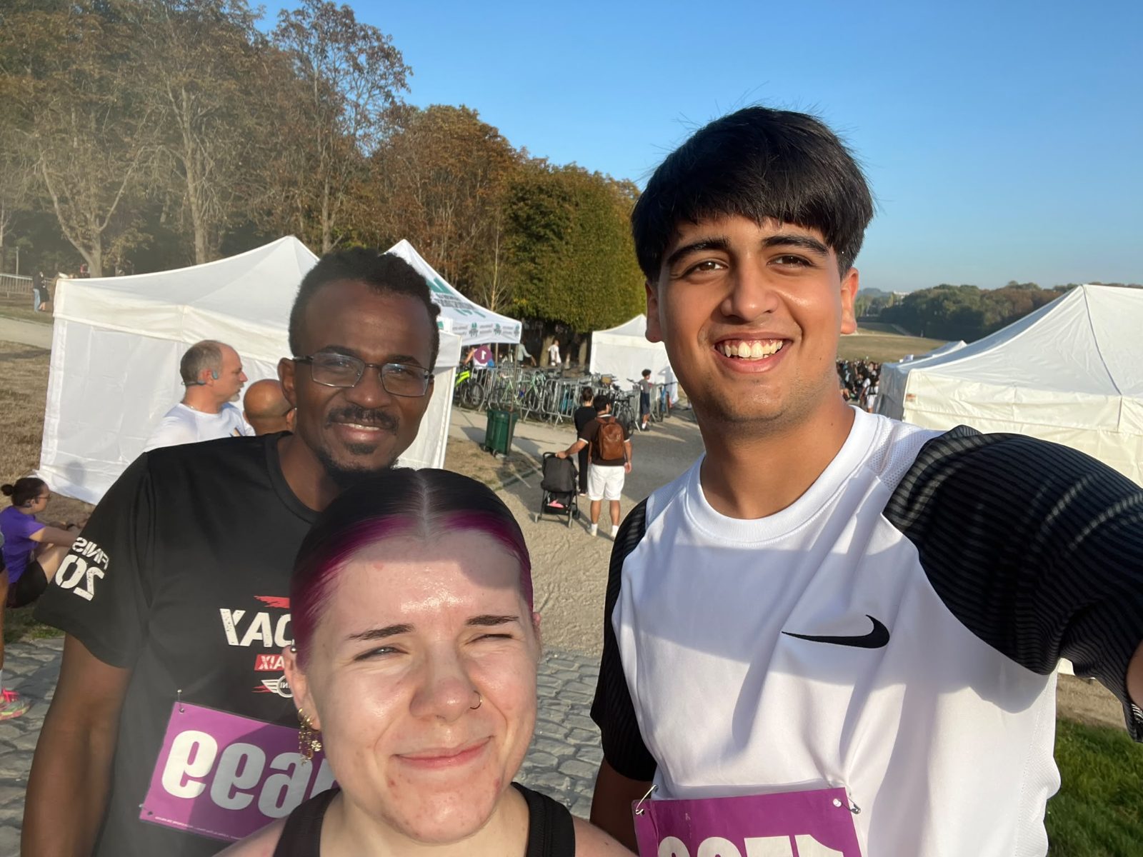 Trois coureurs de l'équipe Plein Fard souriants au village de la Virade du Parc de Sceaux